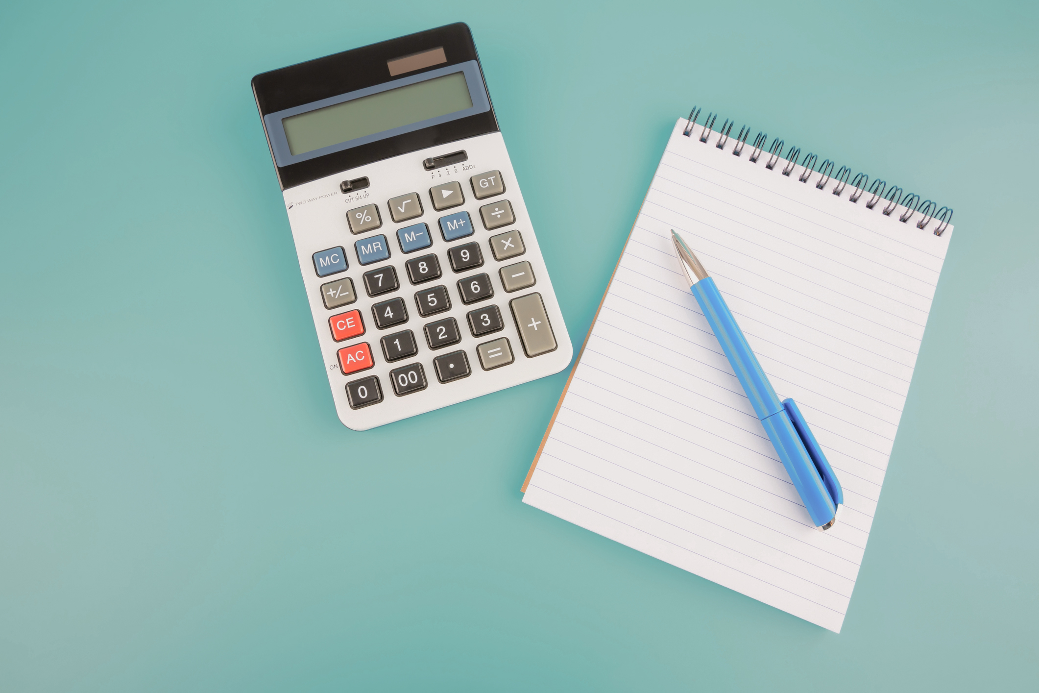 Calculator, blue pen and notepad